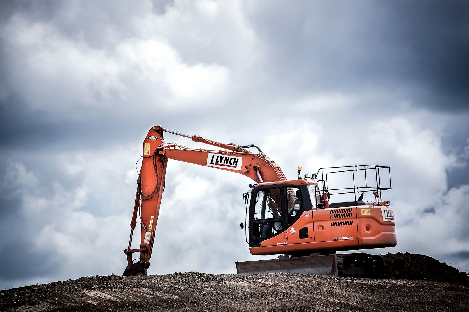 Bagger auf einem Erdwall unter Wolkenhimmel